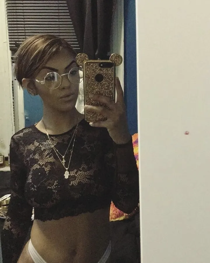 Femme arabe en haut noir à dentelle, prenant un selfie devant un miroir.