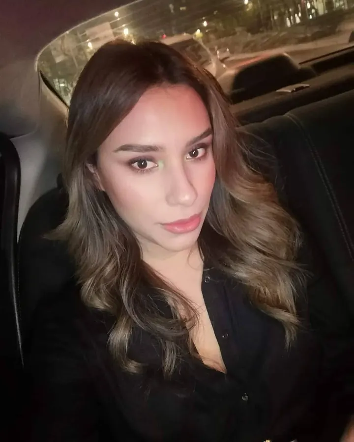Femme arabe aux cheveux châtains, assise dans une voiture, regardant l'objectif.