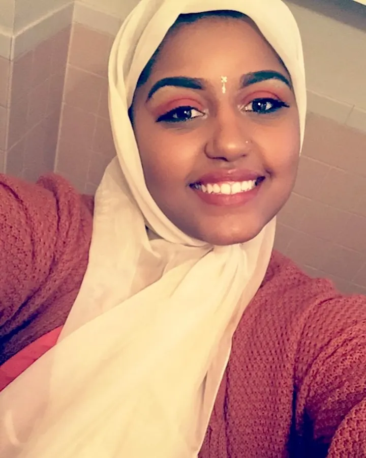 Femme aux cheveux noirs, regard intense, prenant un selfie dans un miroir, visage partiellement visible